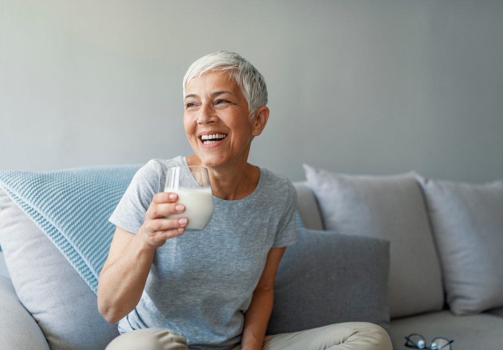 Happy senior woman in menopause holding a glass of milk